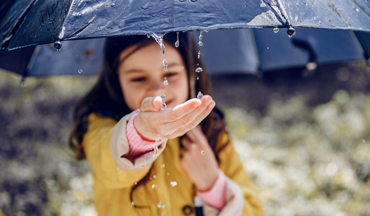 Little girl in a rain coat. Child playing in a park.